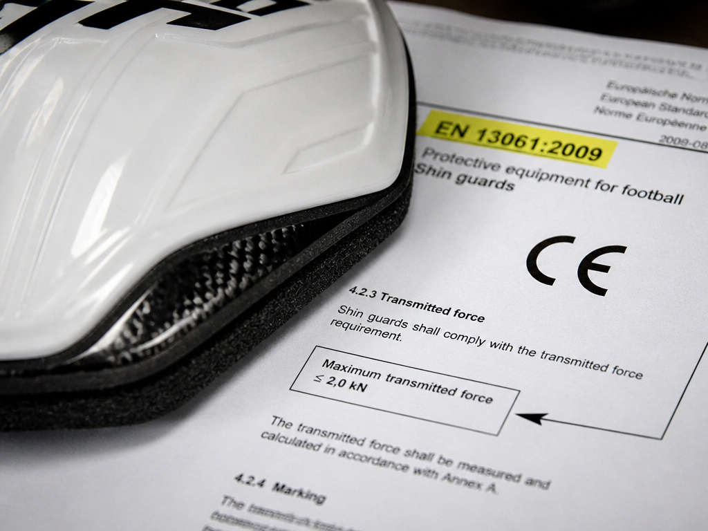 Close-up of shin guard materials and safety standard document with CE mark.
